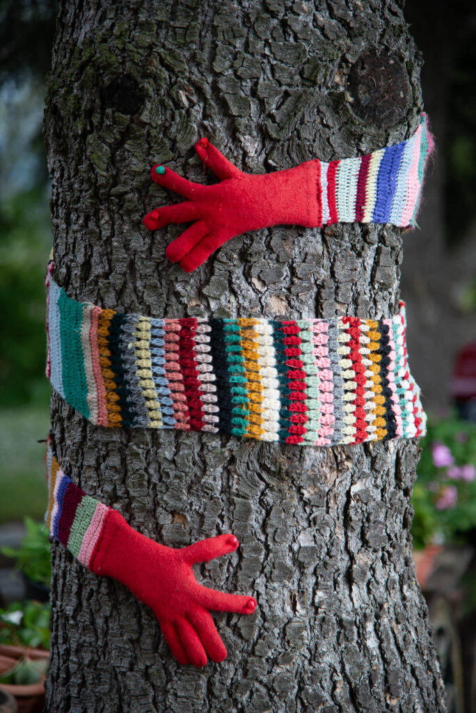 Un albero con una decorazione fatta in crochet che lo abbraccia